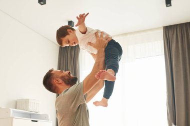 Çocuk uçtuğunu hayal ediyor. Babam onu kucağına aldı. Adam evcil odasında oğluyla oynuyor..