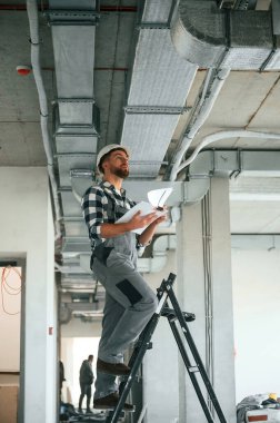 Tavanı kontrol ediyorum. Bitmemiş odada üniformalı inşaat işçisi..