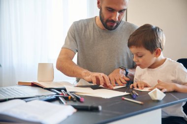 Origami yapmayı öğreniyorum. Baba ve oğul evde, masanın yanındalar..