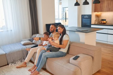 Kanepede. İki küçük çocuklu ebeveynler evcil odada birlikteler..