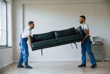Koltuk ellerde. Bir odada hareket eden iki servis çalışanı.