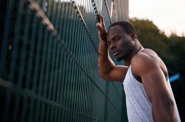 Poz vermek ve ayakta durmak. Yakışıklı siyah adam gündüz vakti dışarıda poz veriyor..