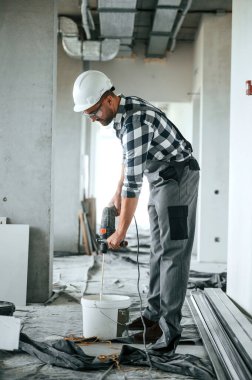 Betonu karıştırıyorum. Üniformalı tamirci tamamlanmamış binada..