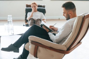 Hayat sorunları. Kadın bir psikologla randevuda sandalyede oturuyor..