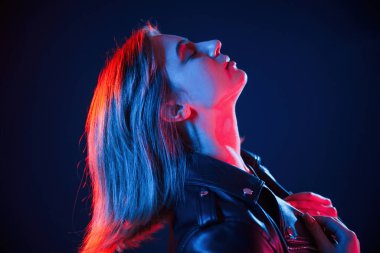 Koyu mavi arka plana karşı. Neon renkli güzel bir kadın portresi..