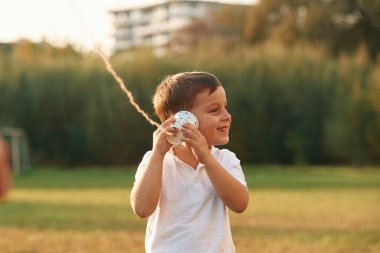 Telli telefon kullanmak. Küçük çocuk gündüz vakti dışarıda oynuyor..