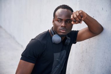 Boynunda kulaklıkla. Yakışıklı siyah adam gündüz vakti dışarıda poz veriyor..