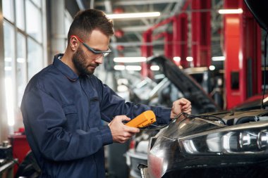 Profesyonel elektro aygıt ellerinde. Araba tamircisi otomobille garajda..