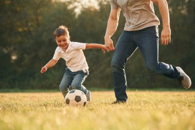 Saha manzarası, futbol topuyla. Baba ve küçük oğlu dışarıda oynuyor ve eğleniyorlar..