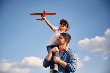 Oyuncak uçakla oynamak, omuzlarda oturmak. Baba ve küçük oğlu dışarıda eğleniyorlar..