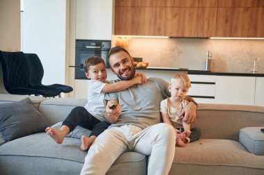 Rahatlama kavramı. İki erkek çocuğu olan baba kanepede oturuyor..