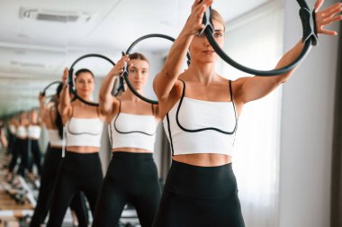 Ayakta, gülümseyen, el ele tutuşan. Spor salonundaki kadınlar egzersiz yapıyor..