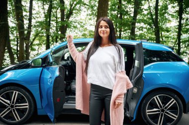 Doğanın ve boş zamanın tadını çıkartıyor, aktif. Neşeli güzel kadın mavi arabanın yanında..