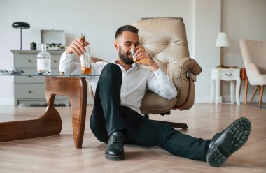 Yerde oturuyordu, üzgündü. Alkolik genç adam içeride..