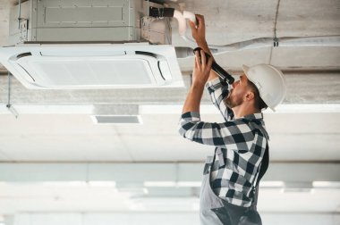 Havalandırma sistemini tavana kuruyorum. Üniformalı tamirci tamamlanmamış binada..