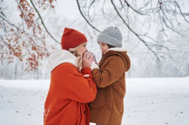 Yan görüş. Anne ve kızı kış çayırlarında ve ormandalar..