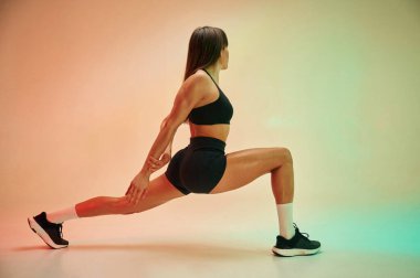 Yan görüş, egzersiz yapmak. Spor elbiseli genç bayan stüdyoda..