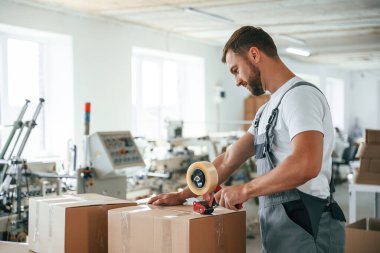 Ürünü paketliyorum. Yakışıklı adam ekolojik kutular üreten fabrikada çalışıyor..