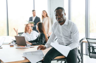 Elinde belgeler olan Afro-Amerikalı bir adam. Bir grup ofis çalışanı içeride birlikte..
