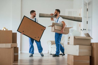 Boyama ve paspas ellerinde. Bir odada hareket eden iki servis çalışanı.