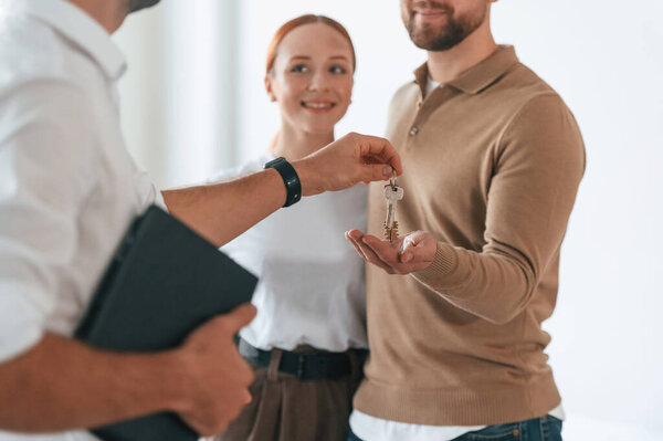 Customers bought the place, receiving the keys. Realtor shows an apartment to a young couple.