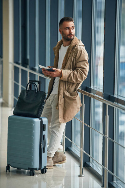 Жду, стою внутри. Молодой красивый мужчина в аэропорту.