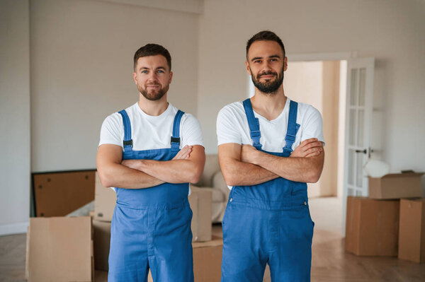 Стоя и позируя. Два работника службы переезда в номере.