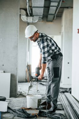 Matkapla. Üniformalı tamirci tamamlanmamış binada..