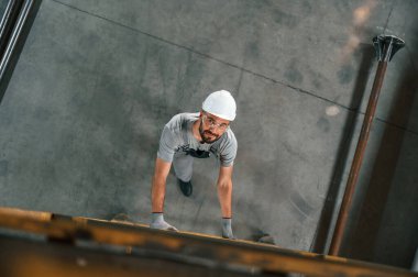 Merdivene çıkıyorum, üst manzara. Gri üniformalı genç fabrika işçisi.