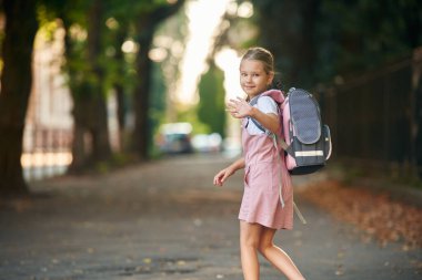 Merhaba el hareketi. Sırt çantalı kız öğrenci dışarıda..