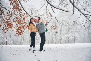 Erkek, kadın ve küçük oğuldan oluşan mutlu bir aile kış çayırında ve ormanda..