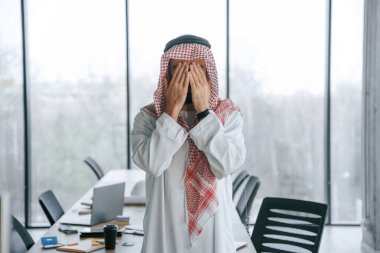 Elleri yüze yakın dua ediyor. Ofisinde geleneksel kıyafetleriyle başarılı bir Müslüman işadamı..