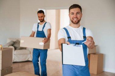 Belgeleri imzalayın. Bir odada hareket eden iki servis çalışanı.