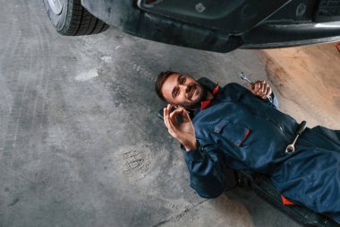 Aletle yere yat. Araba tamircisi otomobille garajda..
