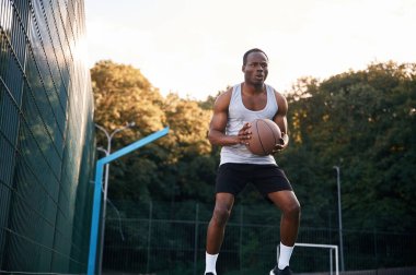 Fotoğraf hareket halinde. Genç siyah adam basketbol topuyla dışarıda..