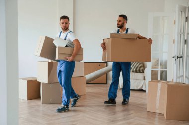 Kutular ellerde. Bir odada hareket eden iki servis çalışanı.