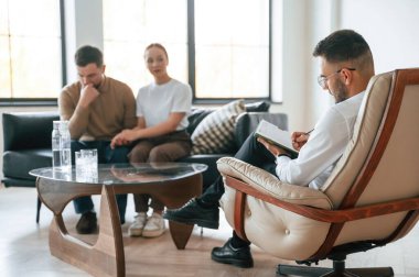 Adam notlar yazıyor. Psikolog randevusundaki çift..