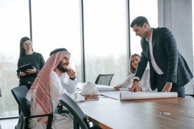 Finansal sorunlar görevi. Geleneksel kıyafetli Müslüman işadamı ve görevde meslektaşları.