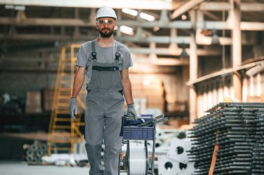 Ön manzara, ileri yürüme. Gri üniformalı genç fabrika işçisi.