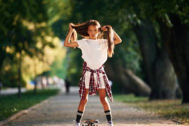 Saçla oynamak, çıldırmak. Dışarıda kaykaylı mutlu küçük kız.