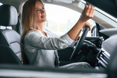 Yan görüş. Kadın arabada oturuyor ve onu sürüyor..