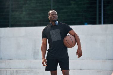 Topu elinde tutuyor. Genç siyah adam.