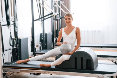 Topu elinde tutuyor. Spor salonundaki genç kadın egzersiz yapıyor..