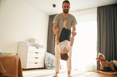 Oynuyor, el ele tutuşuyor. Adam evcil odasında oğluyla oynuyor..