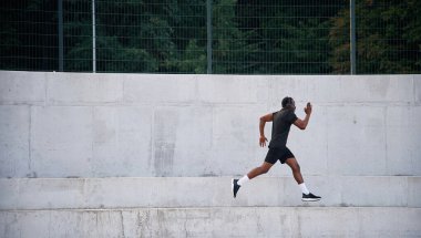 Yan görüş. Sportif siyah adam koşuyor, sabah rutini..