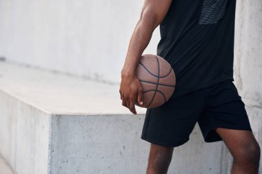 Manzarayı kapat. Genç siyah adam basketbol topuyla dışarıda..