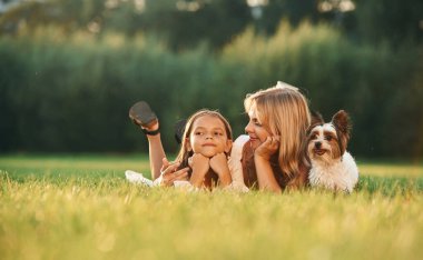 Rahatlıyor, uzanıyor. Anne kızıyla ve sevimli köpeğiyle açık arazide..