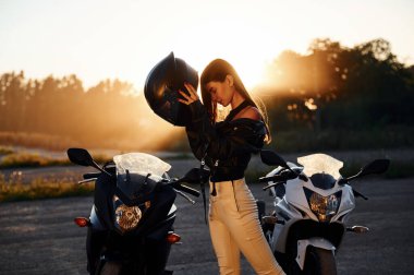 Koruyucu miğferi takıyordu. Dışarıda motosikletli bir kadın var..