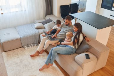 Kanepede. İki küçük çocuklu ebeveynler evcil odada birlikteler..