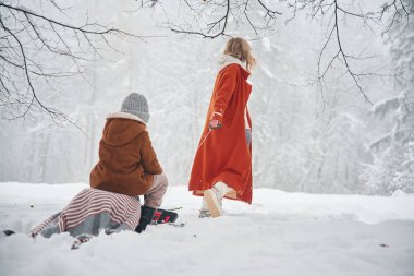 Kızağa binmek. Anne ve kızı kış çayırlarında ve ormandalar..
